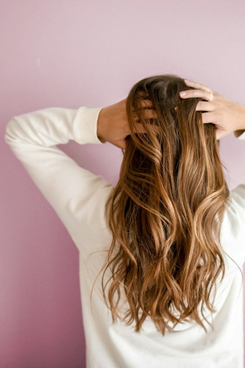 Woman with long blonde hair styled in soft bouncy loose heatless curls in bright morning light