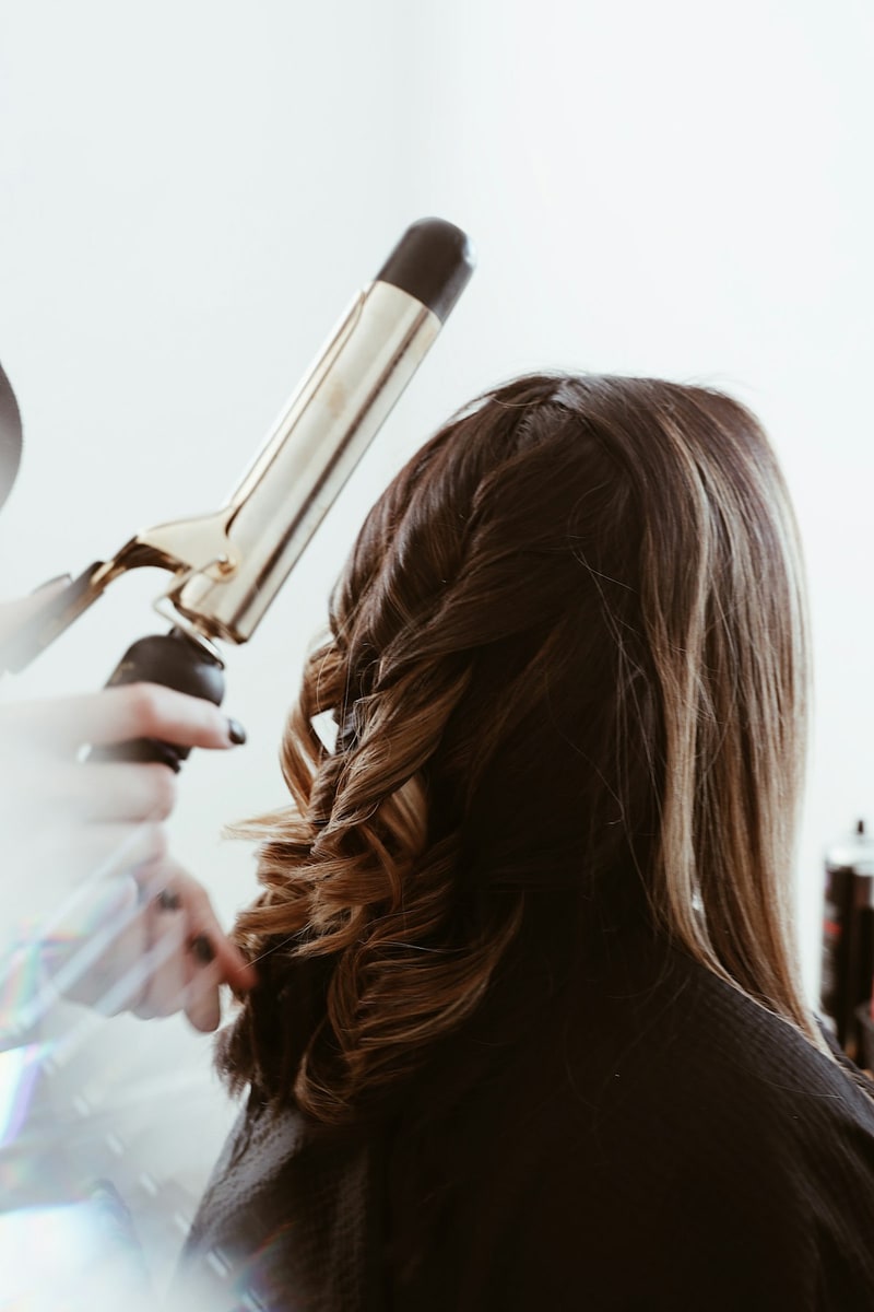 Romantic low twisted updo at the nape of the neck in light-brown hair secured with visible gold bobby pins